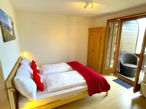 a bedroom with a bed with white sheets and red pillows at SwissHut Stunning Views Alps Lake - Apart. Ringold Down in Sigriswil