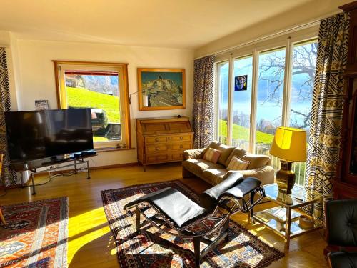 a living room with a couch and a flat screen tv at SwissHut Stunning Views Alps Lake - Chalet Chrutzwag in Sigriswil