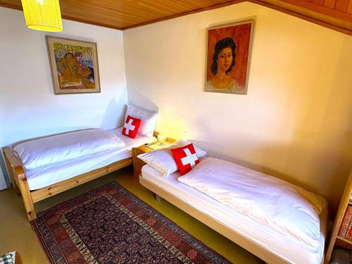 two beds in a room with a picture on the wall at SwissHut Stunning Views Alps Lake - Chalet Chrutzwag in Sigriswil