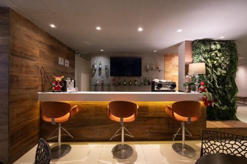 a bar with three stools in a room at Hotel Heritage in Sao Paulo