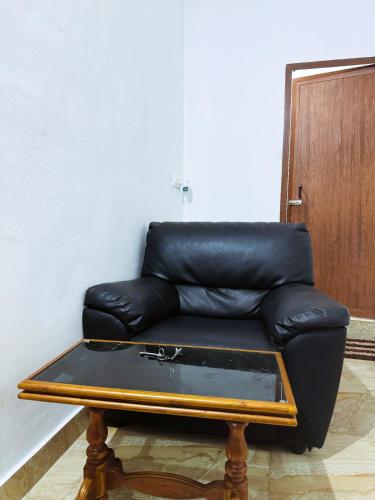 a black leather couch sitting in a room with a table at VCS Apartments Parassinikadavu in Parassinikadavu