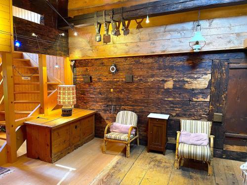 a room with two chairs and a wooden wall at SwissHut Stunning Views Alps Lake - Apart. Erli Down in Därligen