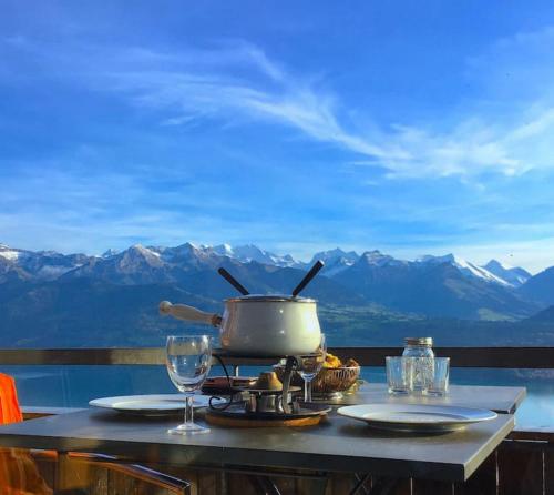 a table with a pot on a stove with mountains in the background at SwissHut Modern Chalet with Spa - Chalet Beunden in Beatenberg