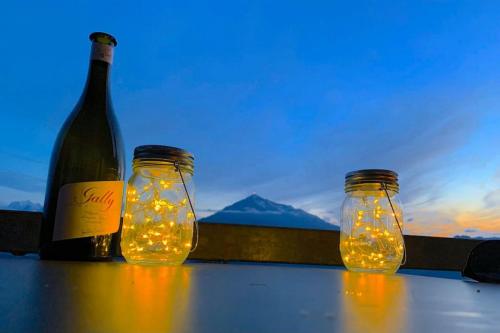 a bottle of wine and two mason jars with lights at SwissHut Modern Chalet with Spa - Chalet Beunden in Beatenberg