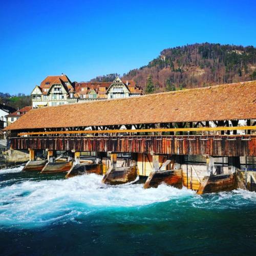 a wooden bridge over a river with waves at SwissHut Modern Chalet with Spa - Chalet Beunden in Beatenberg