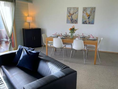 a living room with a table and a leather couch at SwissHut Stunning Views Alps Lake - Chalet Aeschlen in Sigriswil
