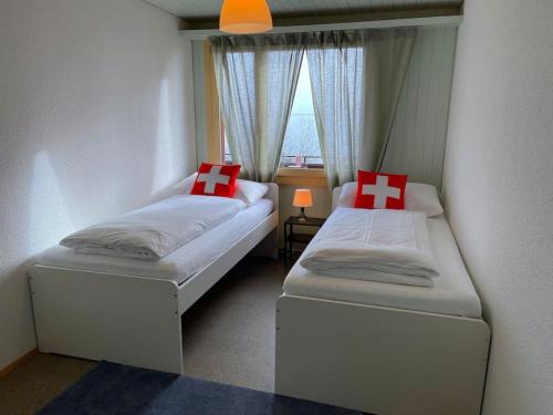 two beds in a small room with a window at SwissHut Stunning Views Alps Lake - Chalet Aeschlen in Sigriswil