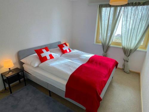 a bedroom with a large bed with red and white pillows at SwissHut Stunning Views Alps Lake - Chalet Aeschlen in Sigriswil