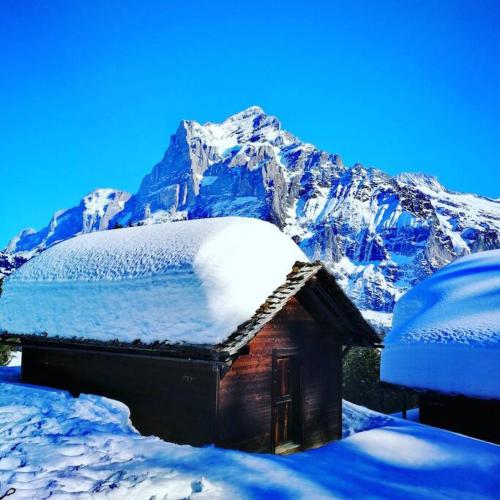 a small house covered in snow in front of a mountain at SwissHut Stunning Views Alps Lake - Chalet Aeschlen in Sigriswil