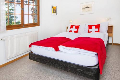 a bedroom with a large bed with red and white pillows at SwissHut Stunning Views Alps Lake - Chalet Emmit in Sigriswil