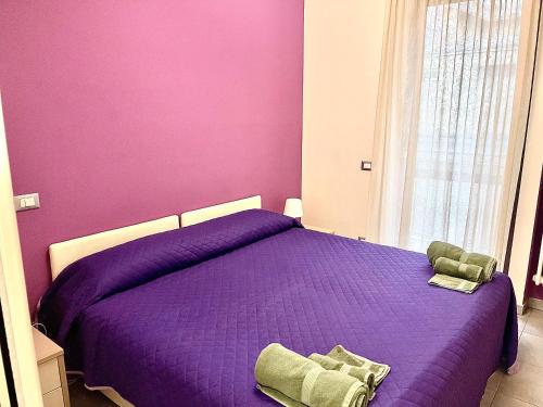 a bedroom with a purple bed and a window at Casa Violetta in Alba