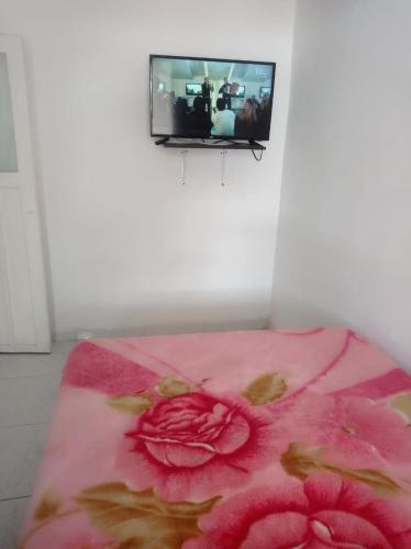 a tv hanging on a wall with a pink blanket at Encanto urbano in Moniquirá