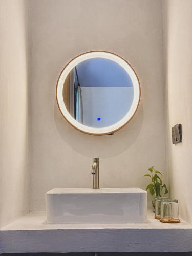 a bathroom sink with a round mirror on the wall at Arunika Villa in Ciloto