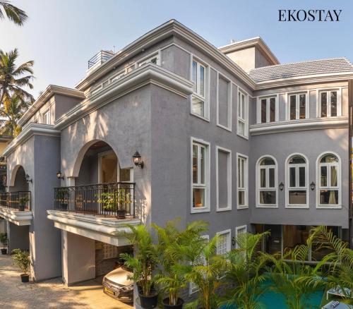 a large gray house with a balcony and palm trees at EKOSTAY - Grey Goose Villa in Calangute