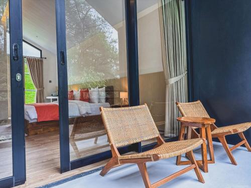 two chairs and a table in a room with a bedroom at Arunika Villa in Ciloto