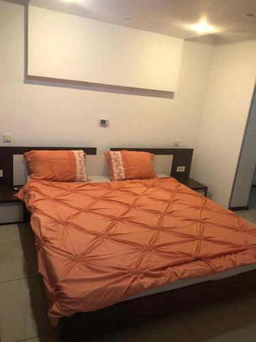 a bed with an orange comforter and two pillows at Centru in Piteşti