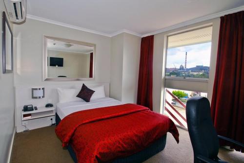 a bedroom with a bed with a red blanket and a window at Isa Hotel in Mount Isa