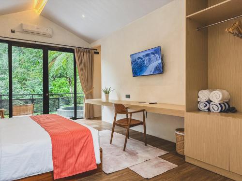 a bedroom with a bed and a desk and a window at Arunika Villa in Ciloto