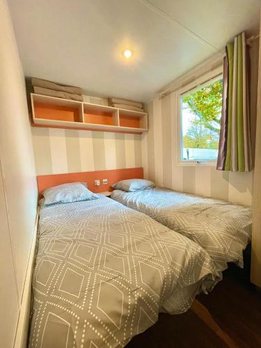 deux lits dans une petite pièce avec une fenêtre dans l'établissement Le Refuge, Mobil Home 3 rooms avec Climatisation, à Samoëns
