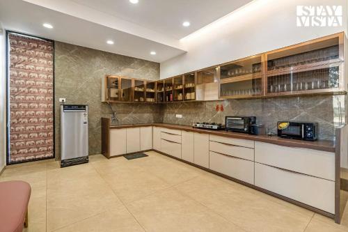a kitchen with white cabinets and a refrigerator at StayVista at The Grand Crest - Presidential Suite in Karjat