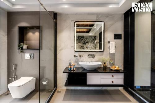 a bathroom with a sink and a glass shower at StayVista at The Grand Crest - Presidential Suite in Karjat