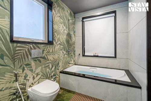 a bathroom with a bath tub and a toilet at StayVista at The Grand Crest - Presidential Suite in Karjat
