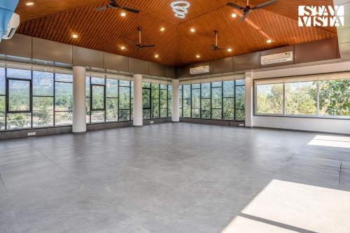 an empty room with a large room with windows at StayVista at The Grand Crest - Presidential Suite in Karjat