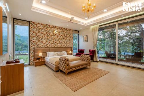 a bedroom with a bed and a chair and windows at StayVista at The Grand Crest - Presidential Suite in Karjat