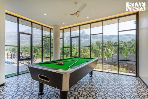 a billiard room with a pool table and windows at StayVista at The Grand Crest - Presidential Suite in Karjat