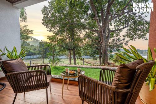 a patio with three chairs and a table with a view at StayVista at The Grand Crest - Presidential Suite in Karjat
