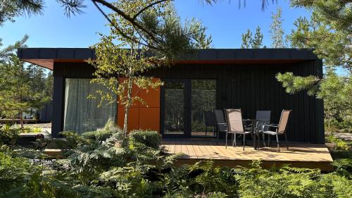 a small black house with a table and chairs on a deck at ForRest Glamp Saulkrasti in Saulkrasti