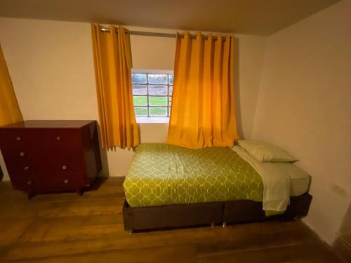a bedroom with a bed with orange curtains and a window at Casa de campo larespampa in Urubamba