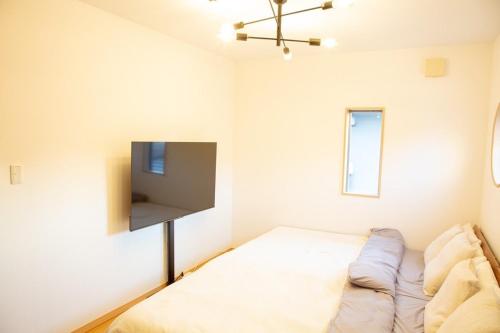 a bedroom with a bed and a flat screen tv at 杏々anan in Kagoshima