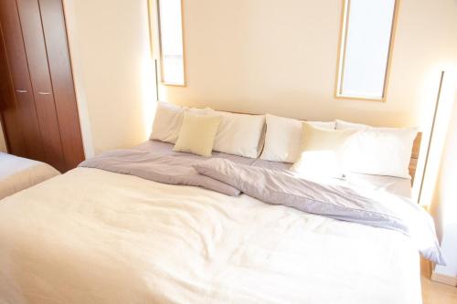 a large bed with white sheets and pillows at 杏々anan in Kagoshima