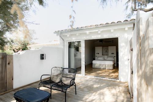 a patio with two chairs and a bed in a bedroom at Mas de la Fouque - Hôtel & Spa in Saintes-Maries-de-la-Mer