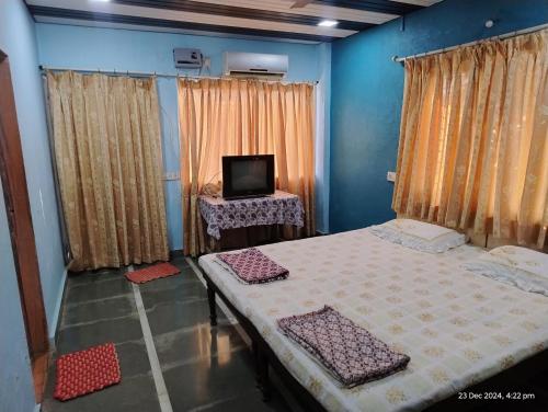 a room with two beds and a tv in it at Gayatri Holiday Home in Murud