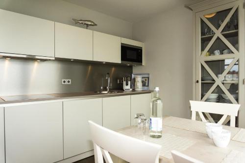 - une cuisine avec des placards blancs et une table avec une bouteille de vin dans l'établissement Ferienresidenz Haus Vogelflug Fehmarn-Ostseeferien "Meerblick-Fehmarnsund" Strandresidenz Vogelflug 147 6, à Fehmarnsund