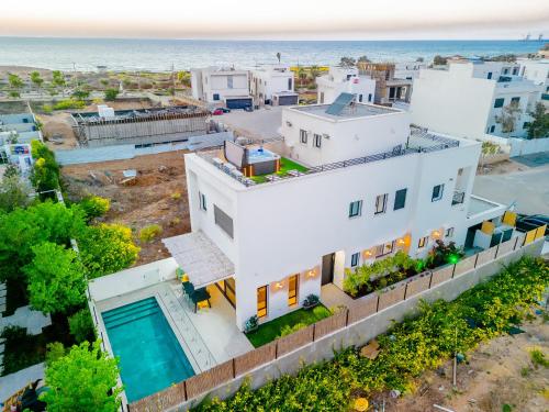 an aerial view of a white house with the ocean in the background at לגונה בלו ביץ-וילה מהממת עם בריכה פרטית וג'קוזי דקה מהים in H̱adera