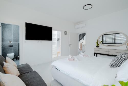 a white room with a bed and a tv at לגונה בלו ביץ-וילה מהממת עם בריכה פרטית וג'קוזי דקה מהים in H̱adera