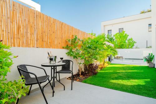 a patio with a table and chairs and grass at לגונה בלו ביץ-וילה מהממת עם בריכה פרטית וג'קוזי דקה מהים in H̱adera