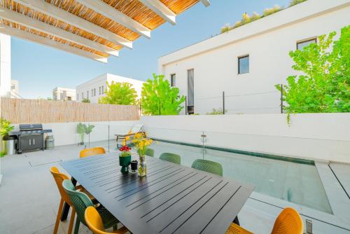 a patio with a table and chairs and a swimming pool at לגונה בלו ביץ-וילה מהממת עם בריכה פרטית וג'קוזי דקה מהים in H̱adera