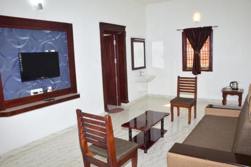 a living room with a couch and a tv at Jeyam Palace by Whynter Stays in Kodaikānāl