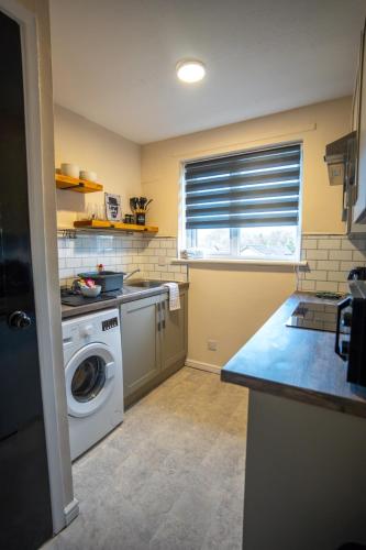 a kitchen with a washing machine and a window at Anderson Apartment in Airdrie