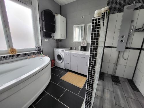 La salle de bains est pourvue d'une baignoire, d'un lavabo et d'un lave-linge. dans l'établissement GÎTE PRIVATIF, MAISON DE VACANCES FAMILIALE 100m2 avec piscine, parking privé 