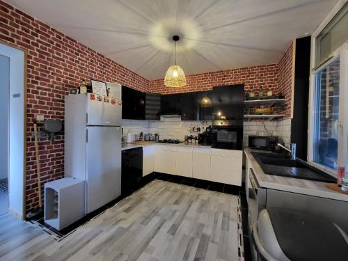 Il comprend une cuisine dotée d'un réfrigérateur blanc et d'un mur en briques. dans l'établissement GÎTE PRIVATIF, MAISON DE VACANCES FAMILIALE 100m2 avec piscine, parking privé 