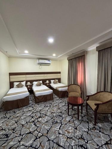 a hotel room with two beds and a table and chairs at نزل وريف المقام للايواء السياحي in Makkah