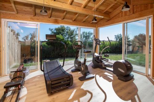 a gym with treadmills and ellipticals in a room with windows at Mas de la Fouque - Hôtel & Spa in Saintes-Maries-de-la-Mer