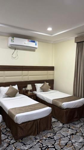 a hotel room with two beds and a tv at نزل وريف المقام للايواء السياحي in Makkah