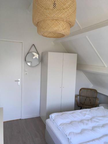 a bedroom with a bed and a lamp and a cabinet at The Beach House in Noordwijkerhout