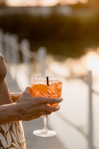 a person holding a glass with a drink at Mas de la Fouque - Hôtel & Spa in Saintes-Maries-de-la-Mer